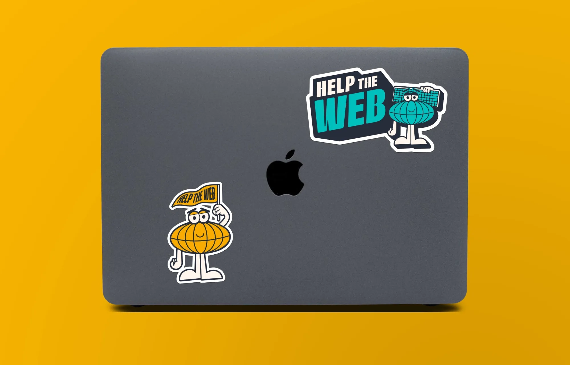 A photo of the back of a Macbook Pro laptop with two Help the Web branded stickers, featuring the mascot, Mr World Wide