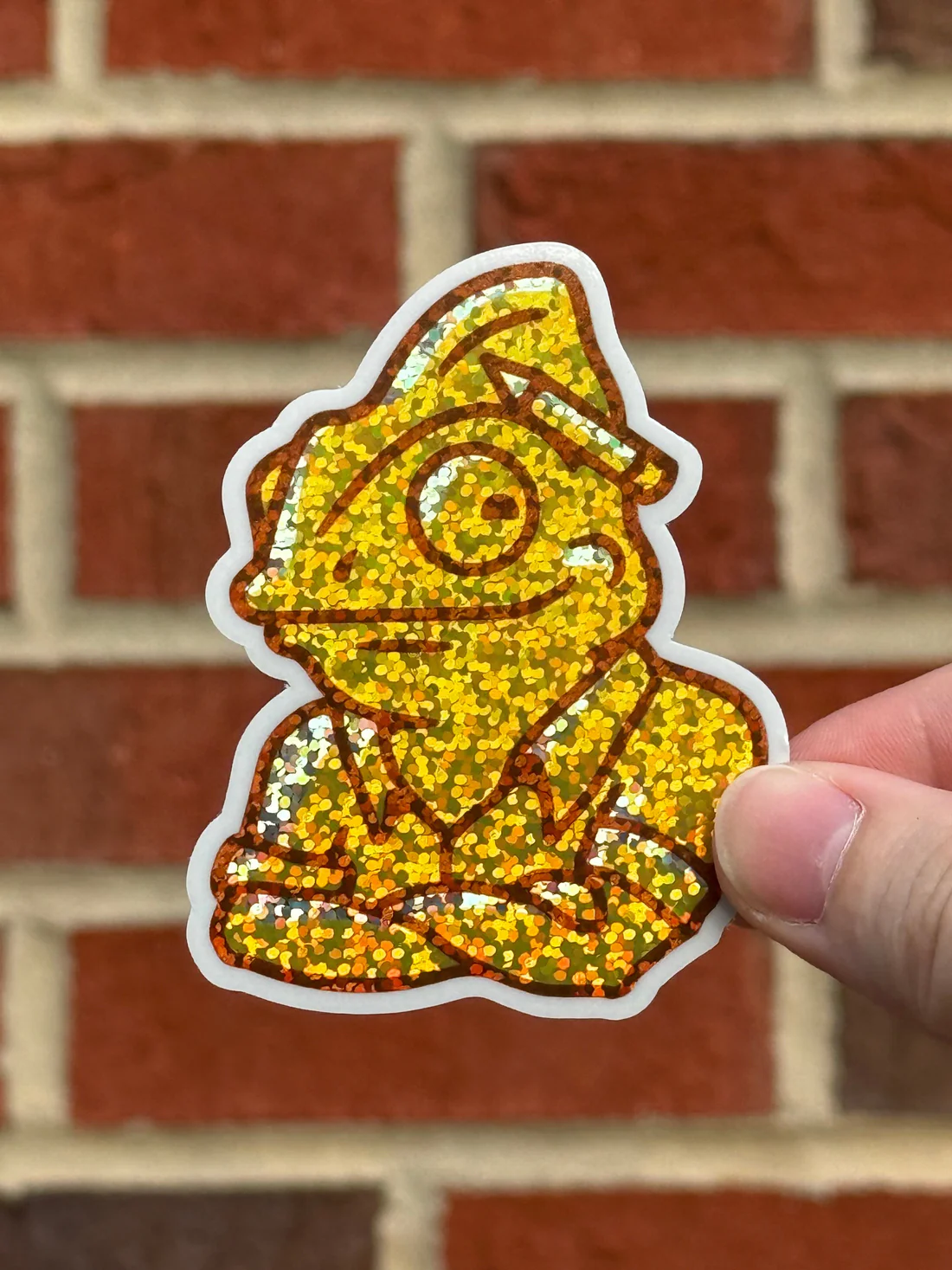 A yellow glitter sticker of Stickymade's chameleon mascot