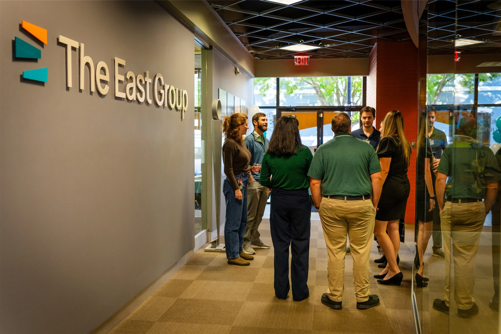 Employees stand around talking at a party in the offices of The East Group