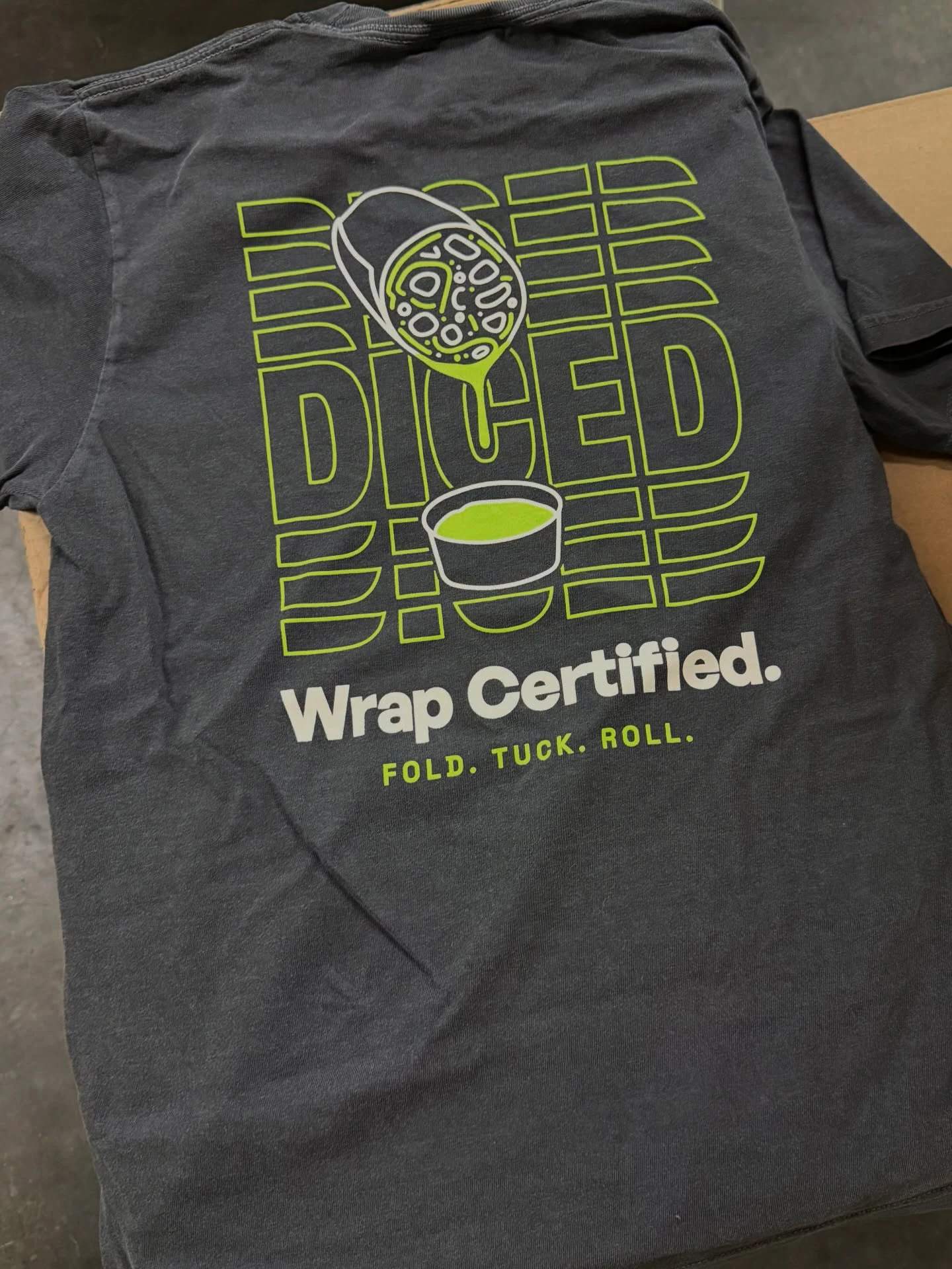 A black shirt with a custom illustration of a wrap on it with the tagline 'Wrapped Certified'