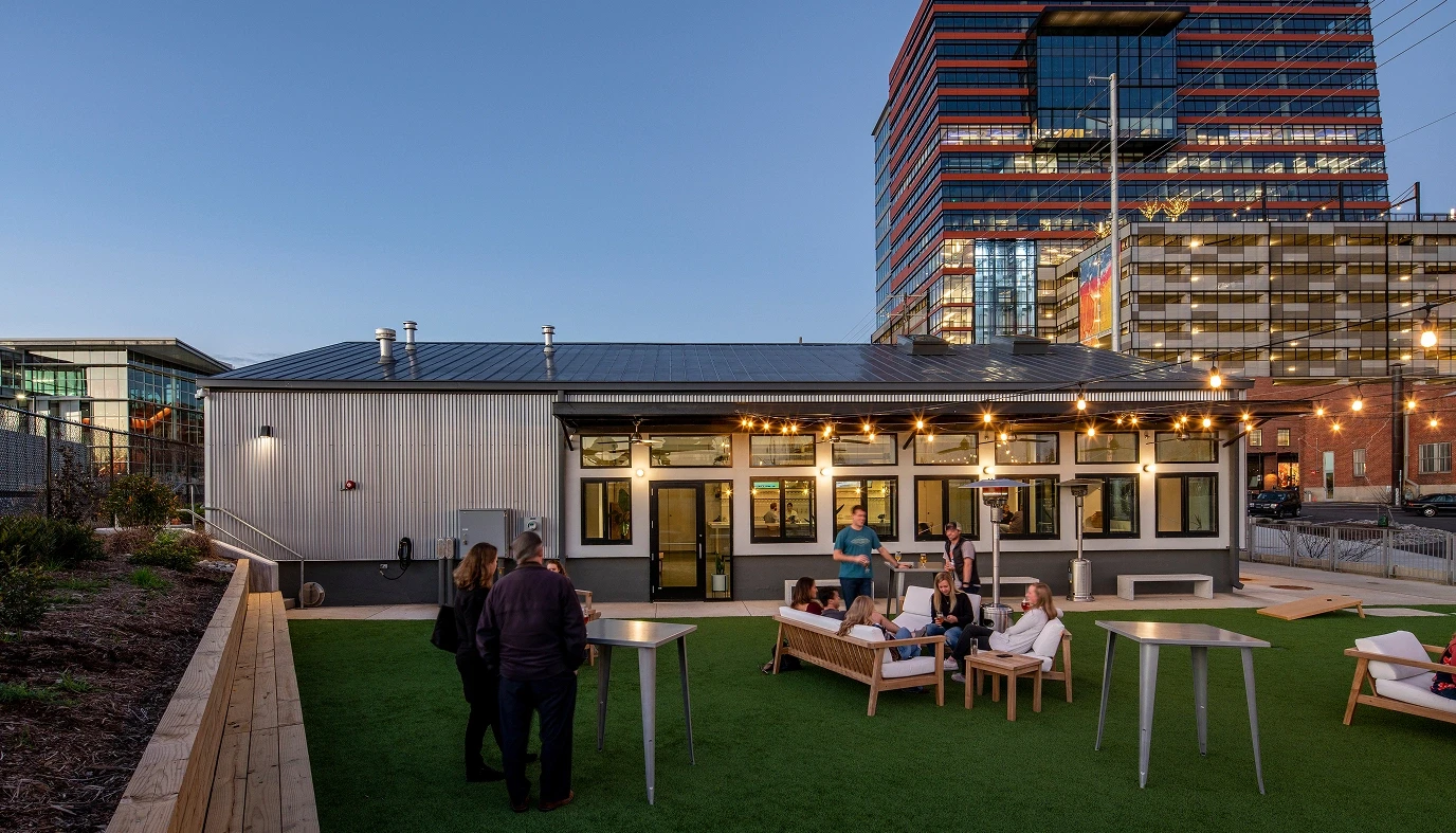 Junction West's outdoor patio at dusk with string lights and people lounging on patio furniture