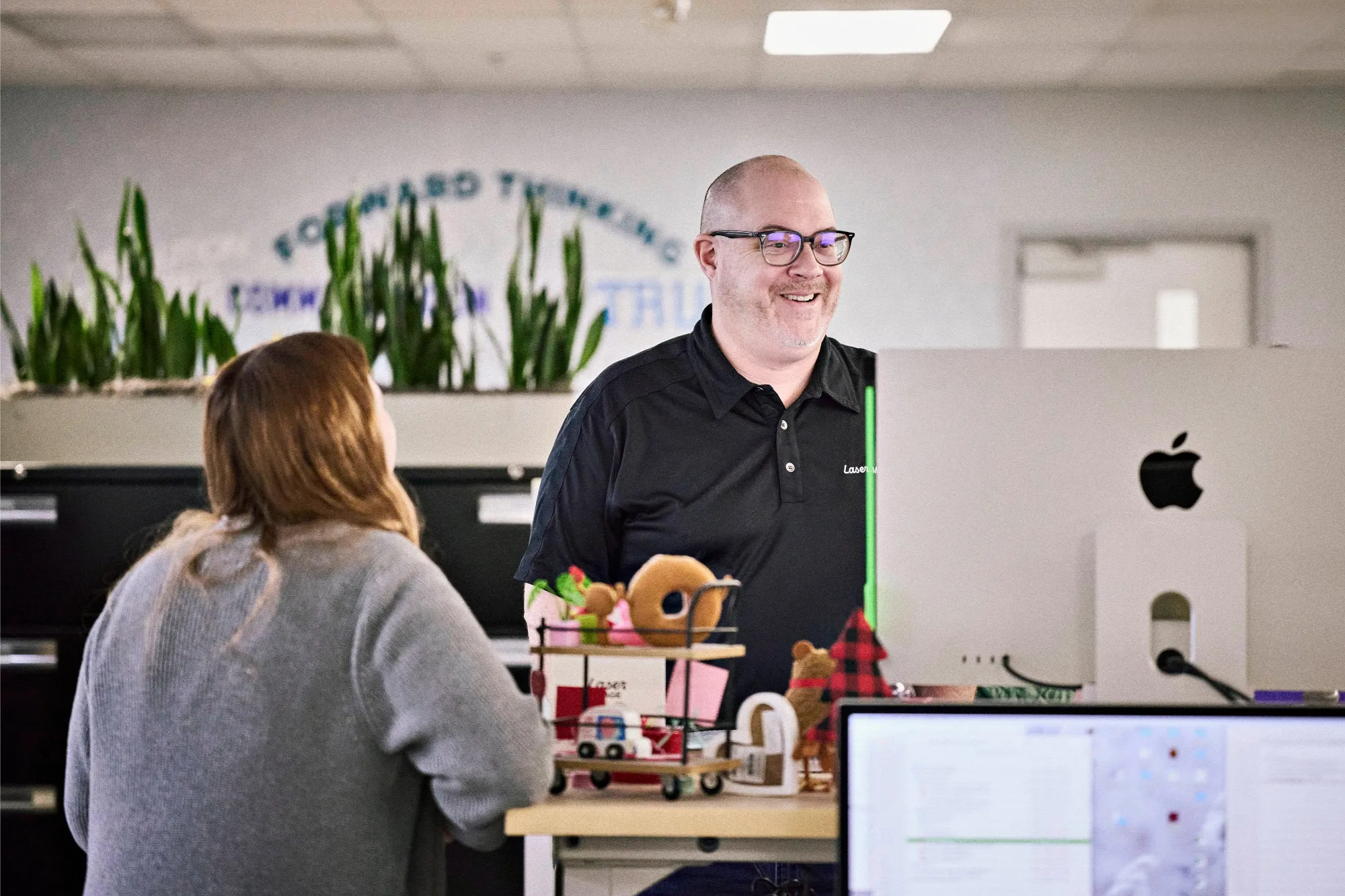 Two employees talking at a desk in the Laser Image front offices
