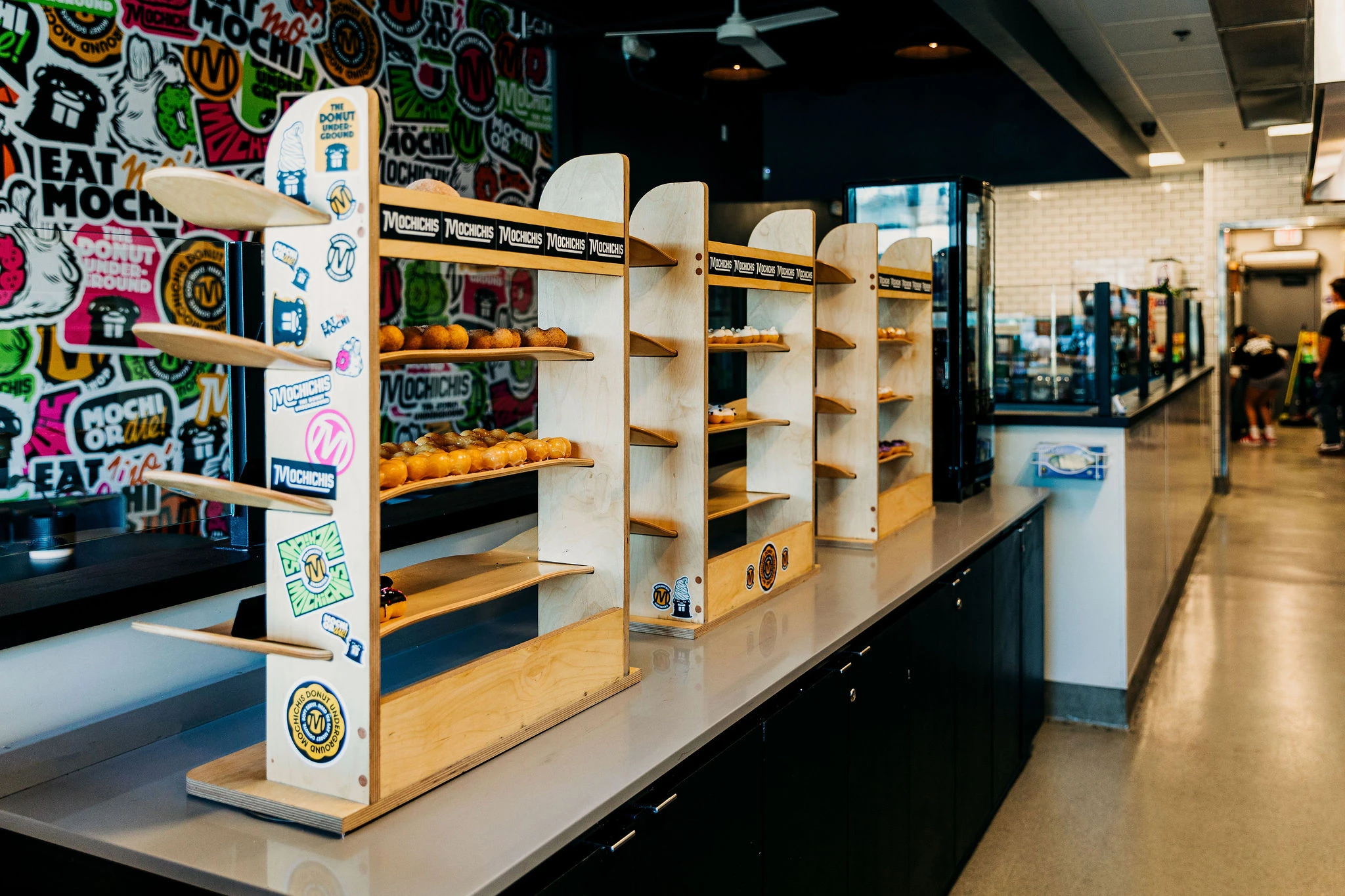 Mochi donuts on shelves made out of skateboards and covered in stickers