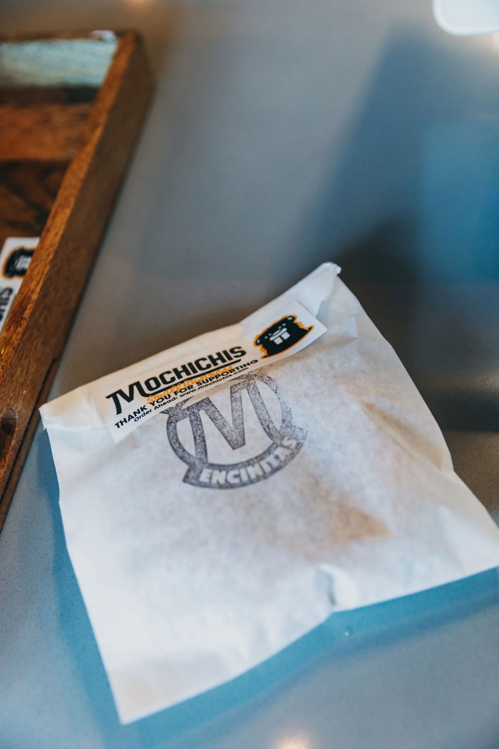 A circular logo badge stamped on a single donut bag for Mochichis