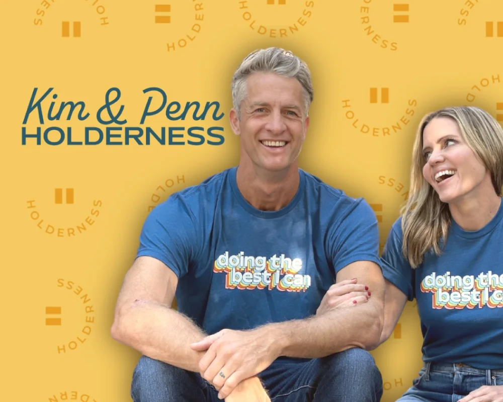 Kim and Pen Holderness sitting in front a branded patterned background