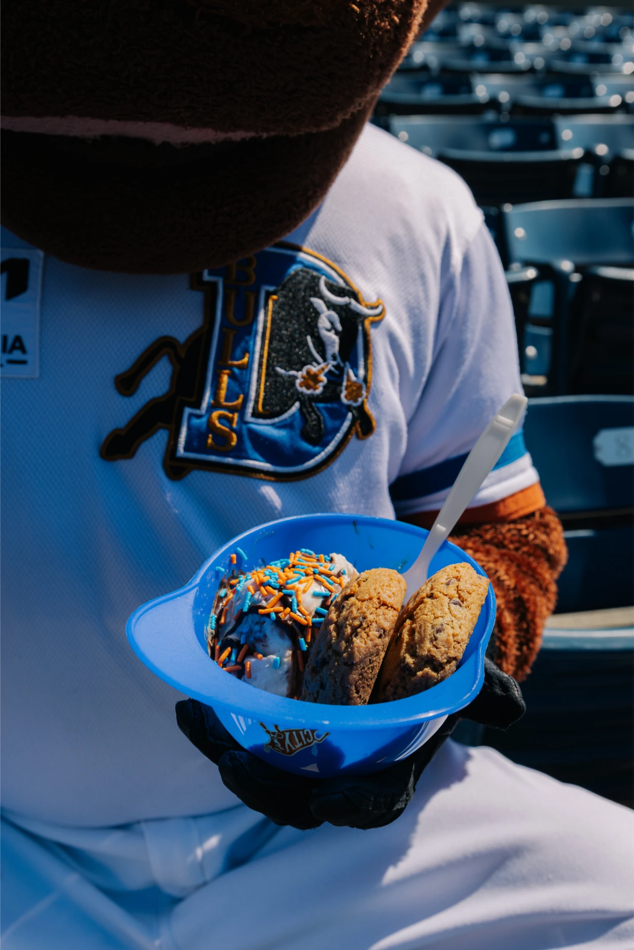 Wool E. Bull, mascot of the Durham Bulls baseball team, holding an ice cream sundae in a baseball helmet cup, in the stands