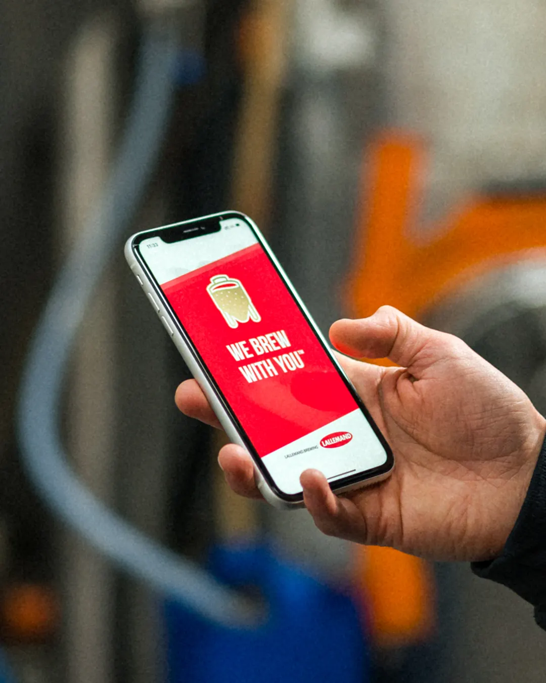 An iPhone being held with a We Brew With You screen