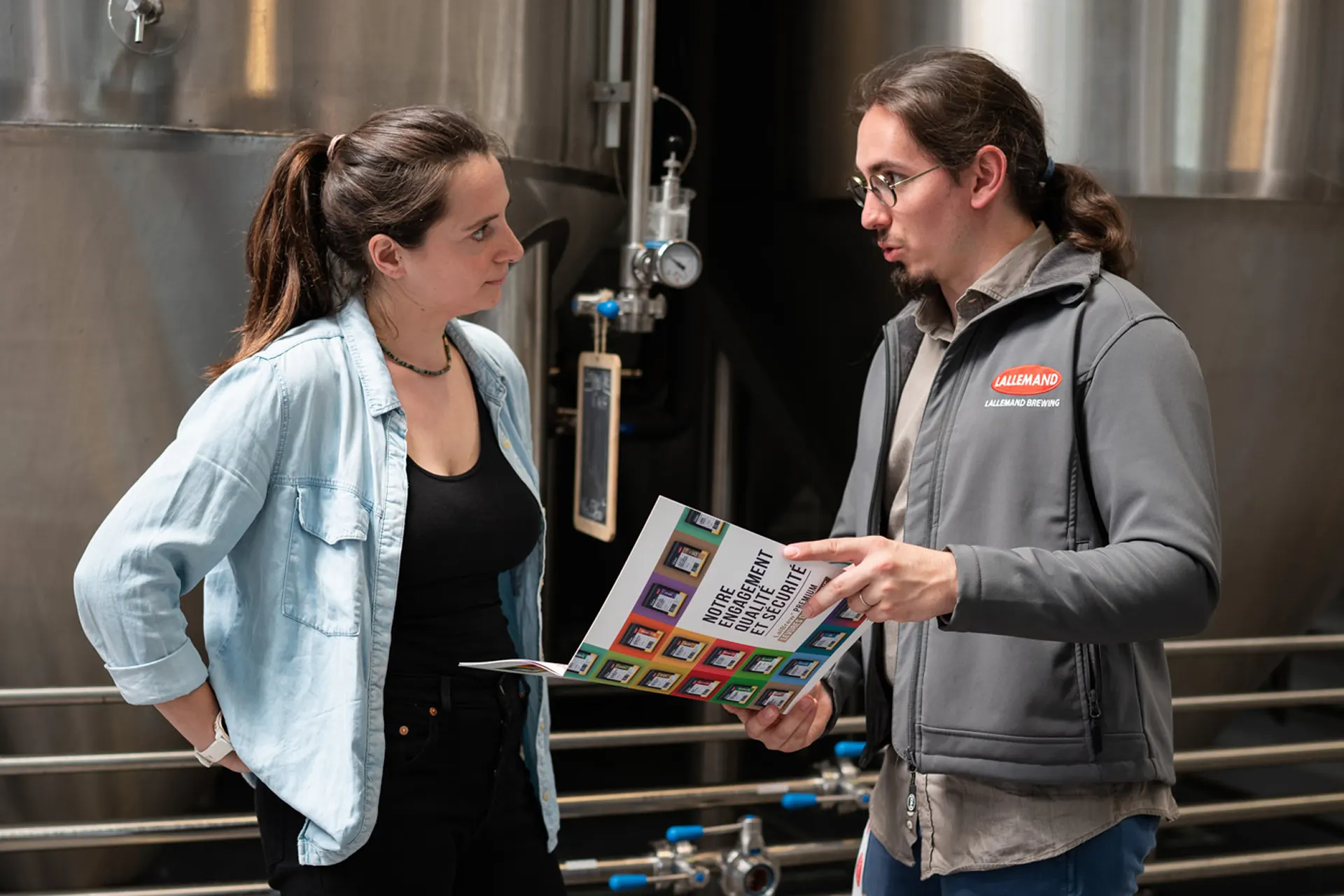 Two Lallemand employees discuss a brochure in a brewery
