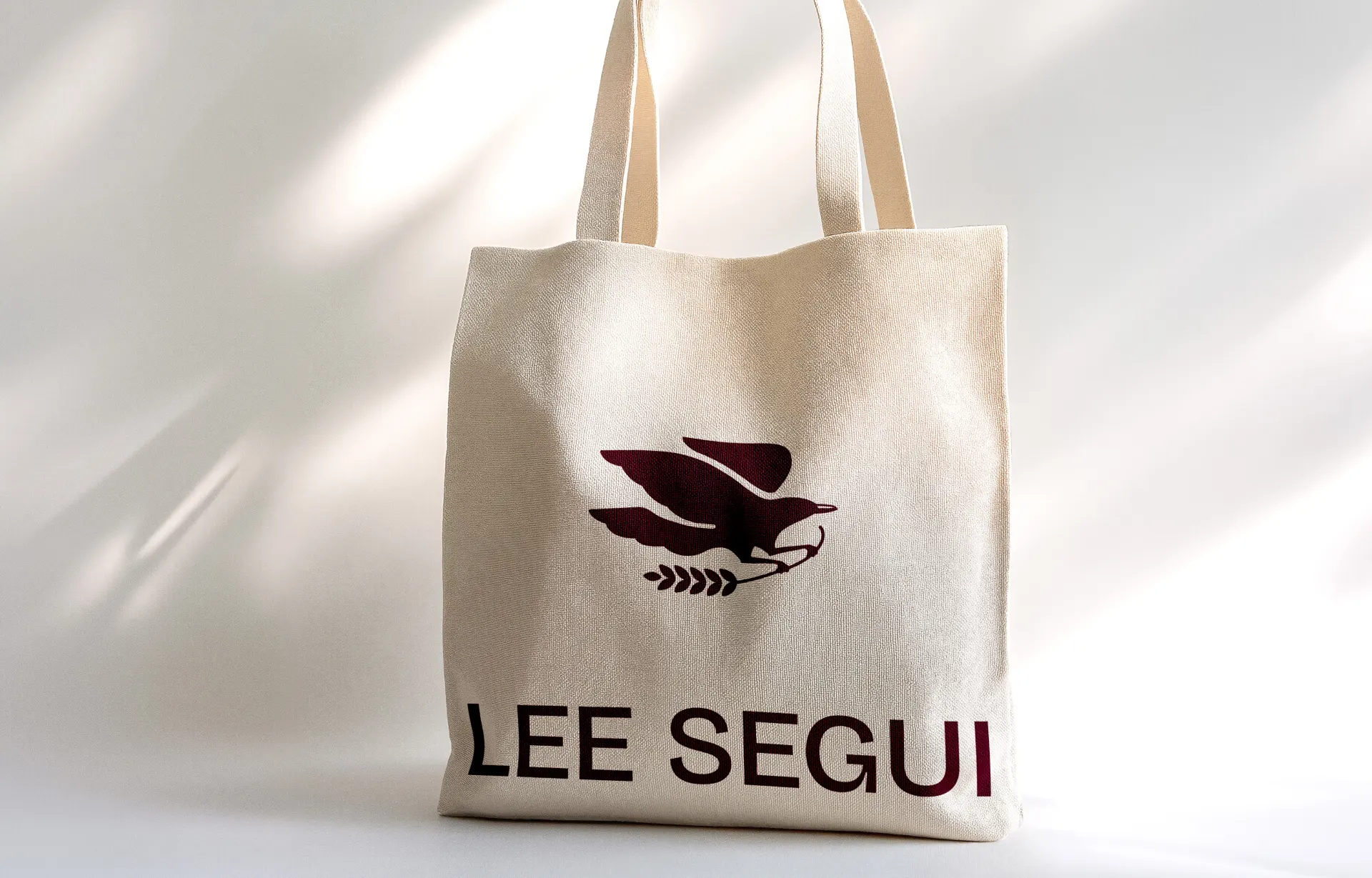 A canvas tote bag with a maroon logo