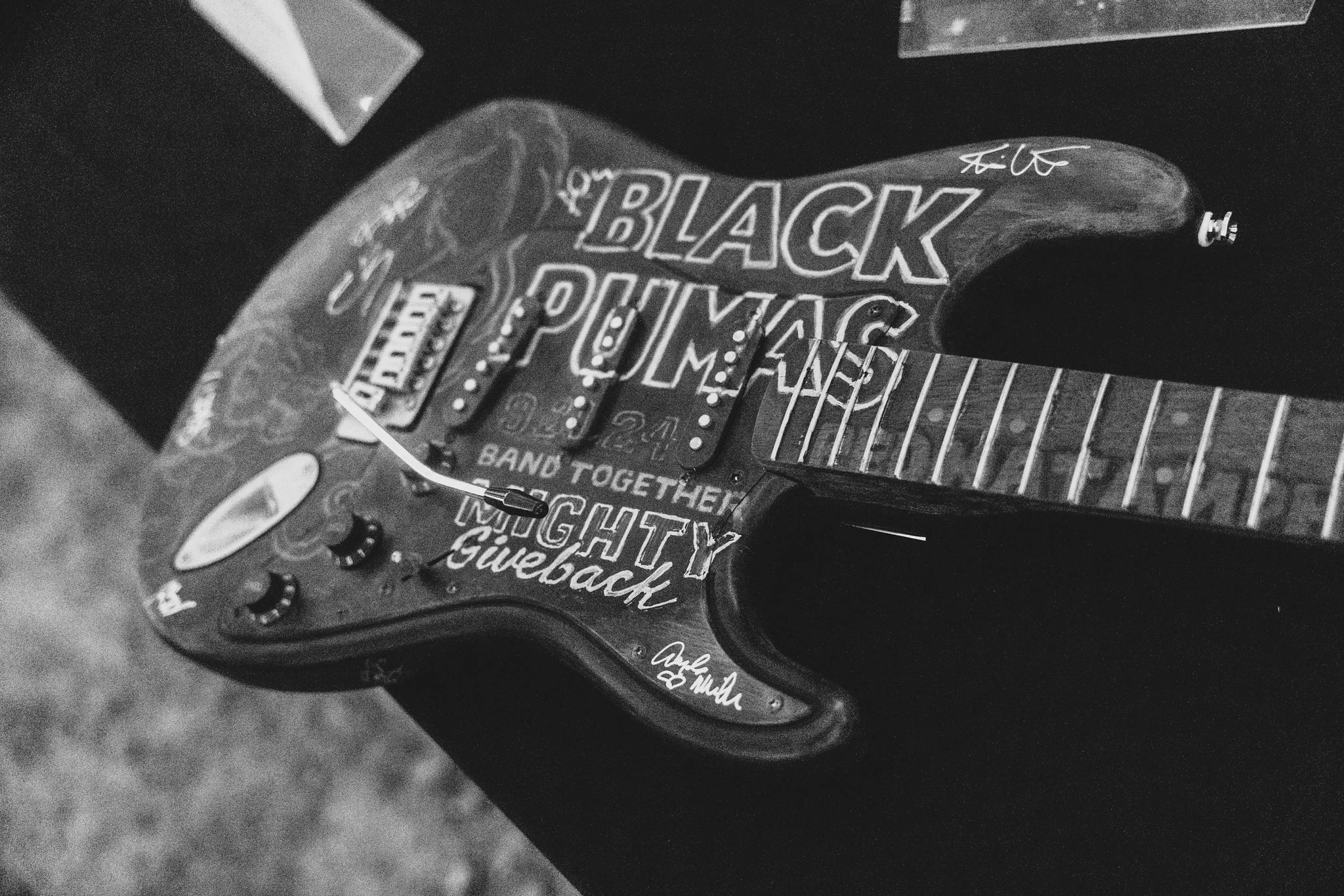 A guitar with Black Pumas and Might Giveback logos drawn on it