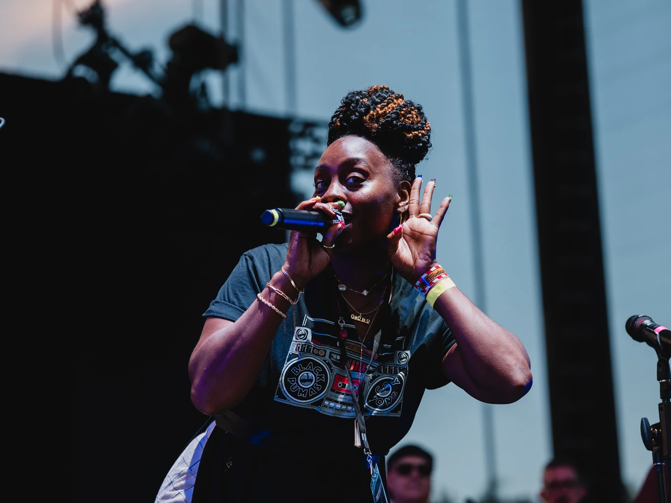A woman on stage, hyping up the crowd and wearing a Mighty Giveback shirt