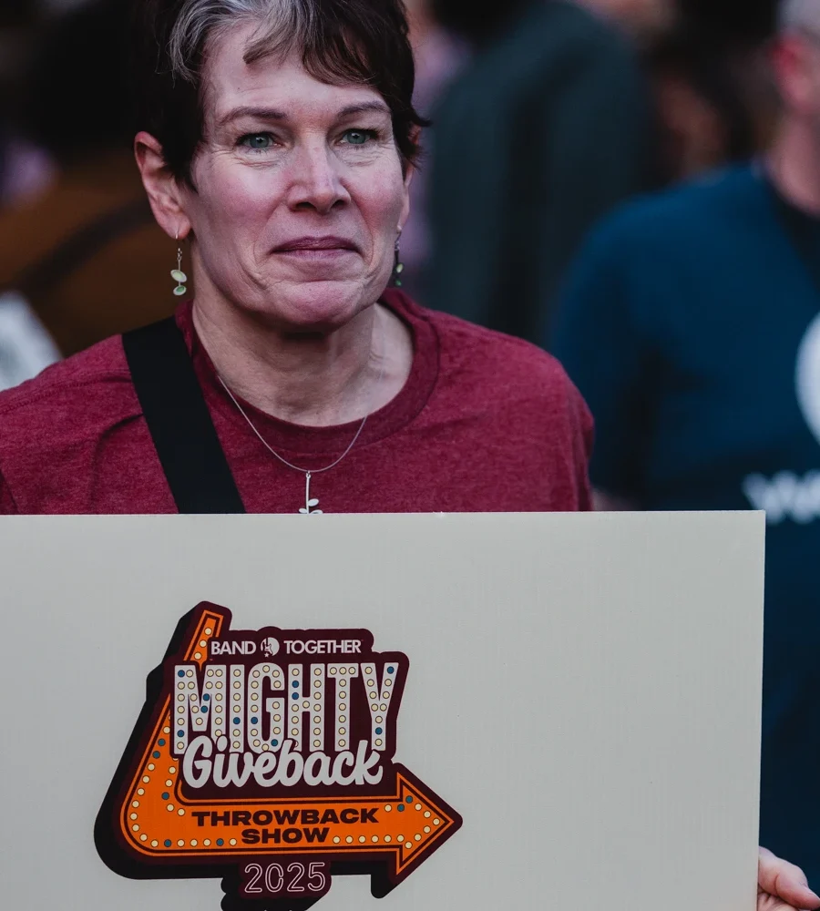 Fan holding a Mighty Giveback 2025 sign