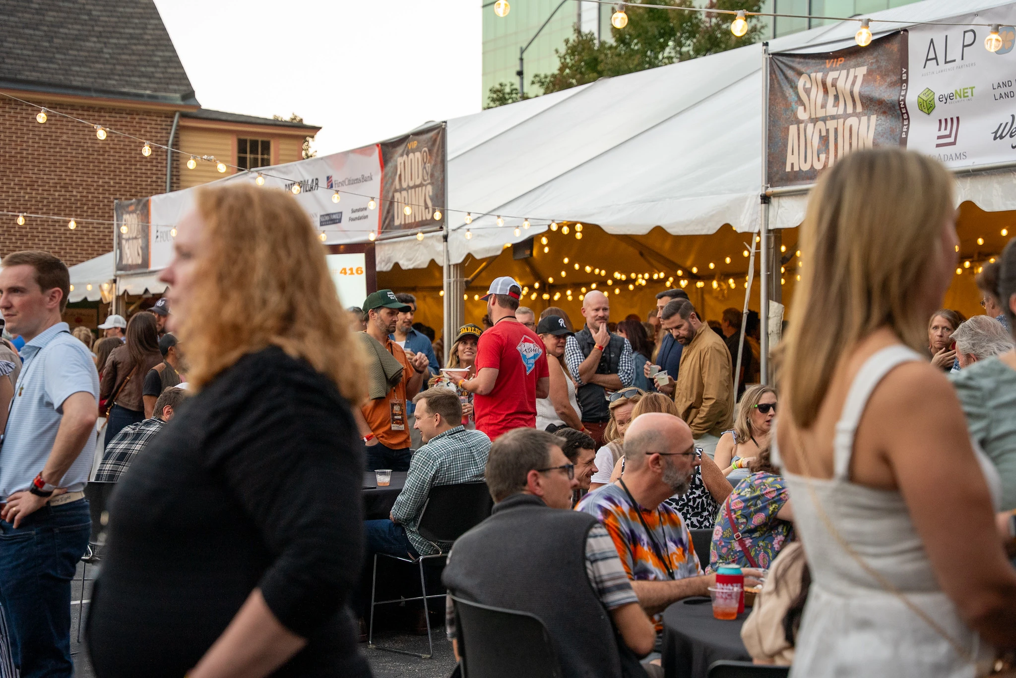 People eating and drinking at Band Together's VIP tents