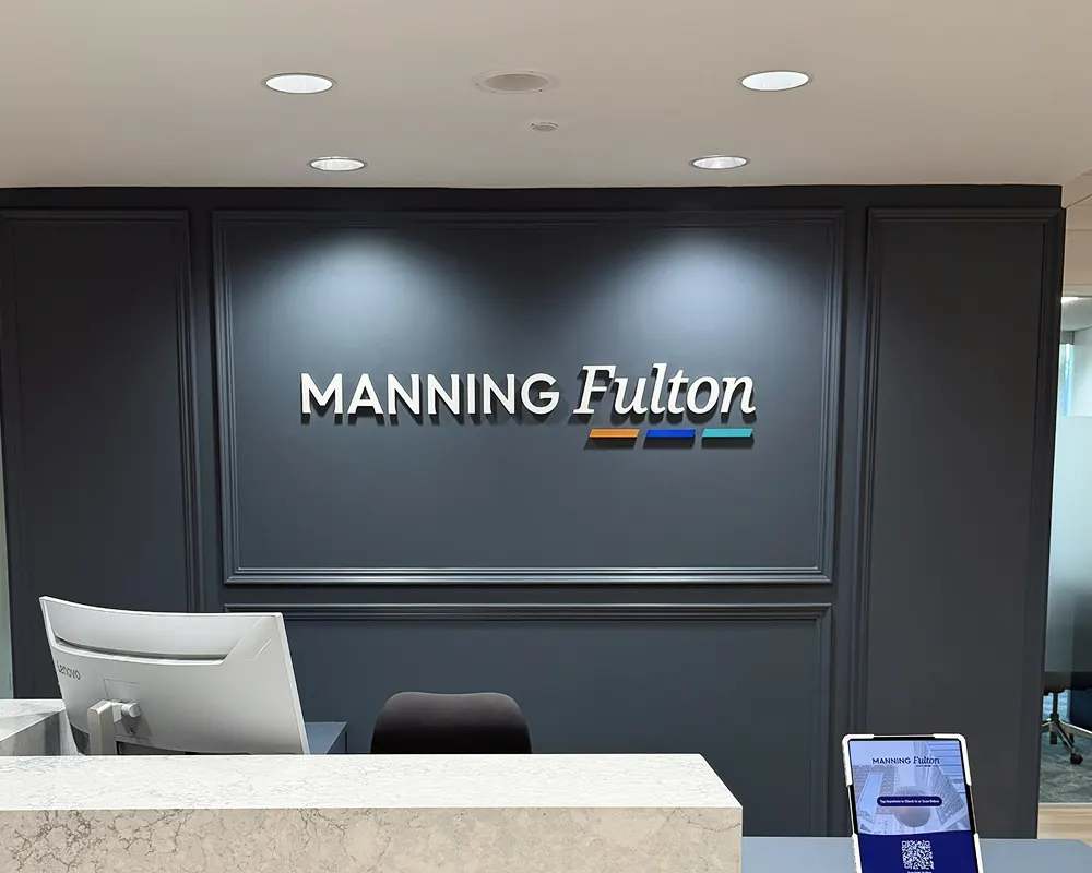 A logo hanging behind the front desk at the Manning Fulton offices at Glenlake V in Raleigh